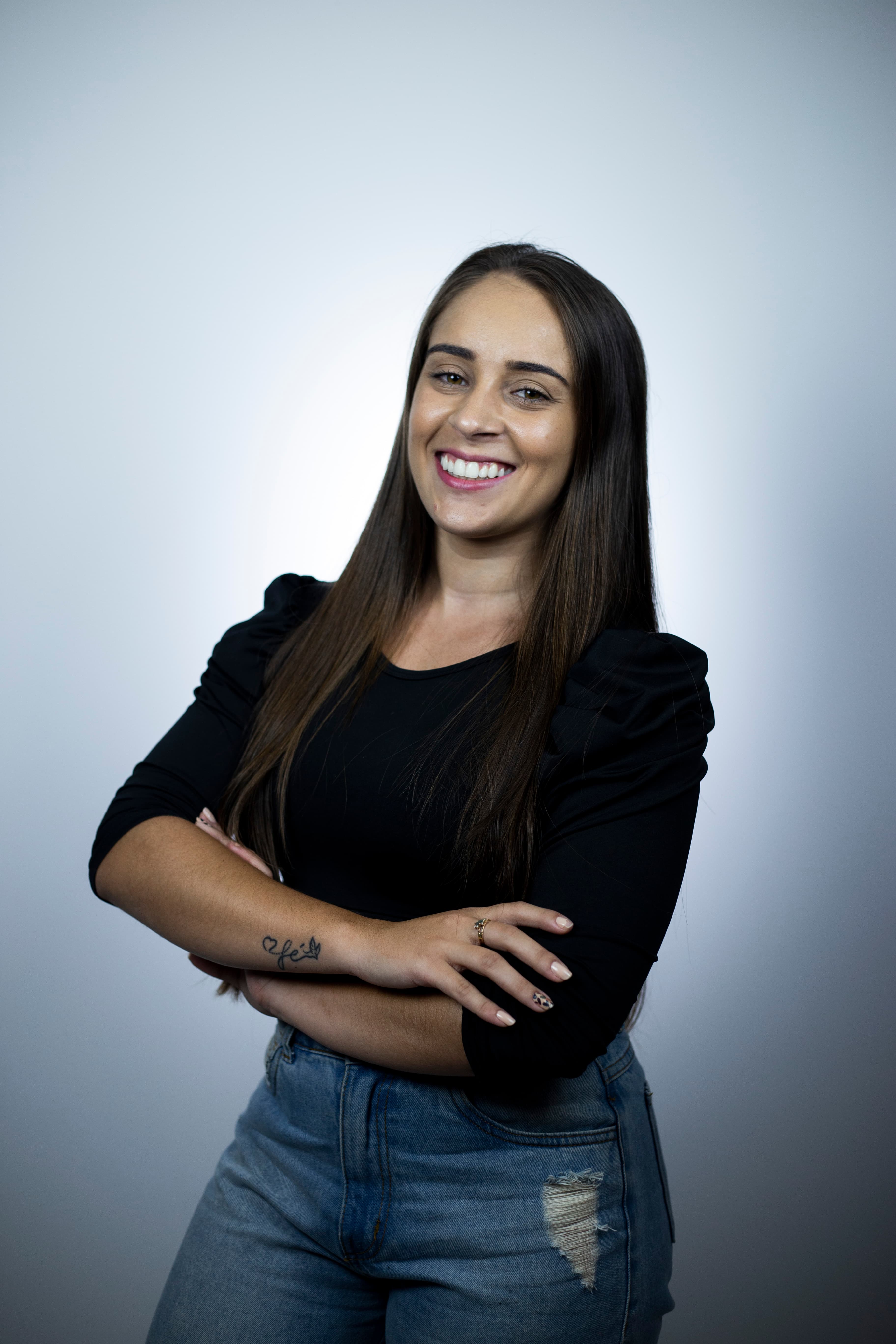 Foto de uma mulher sorrindo com os braços cruzados